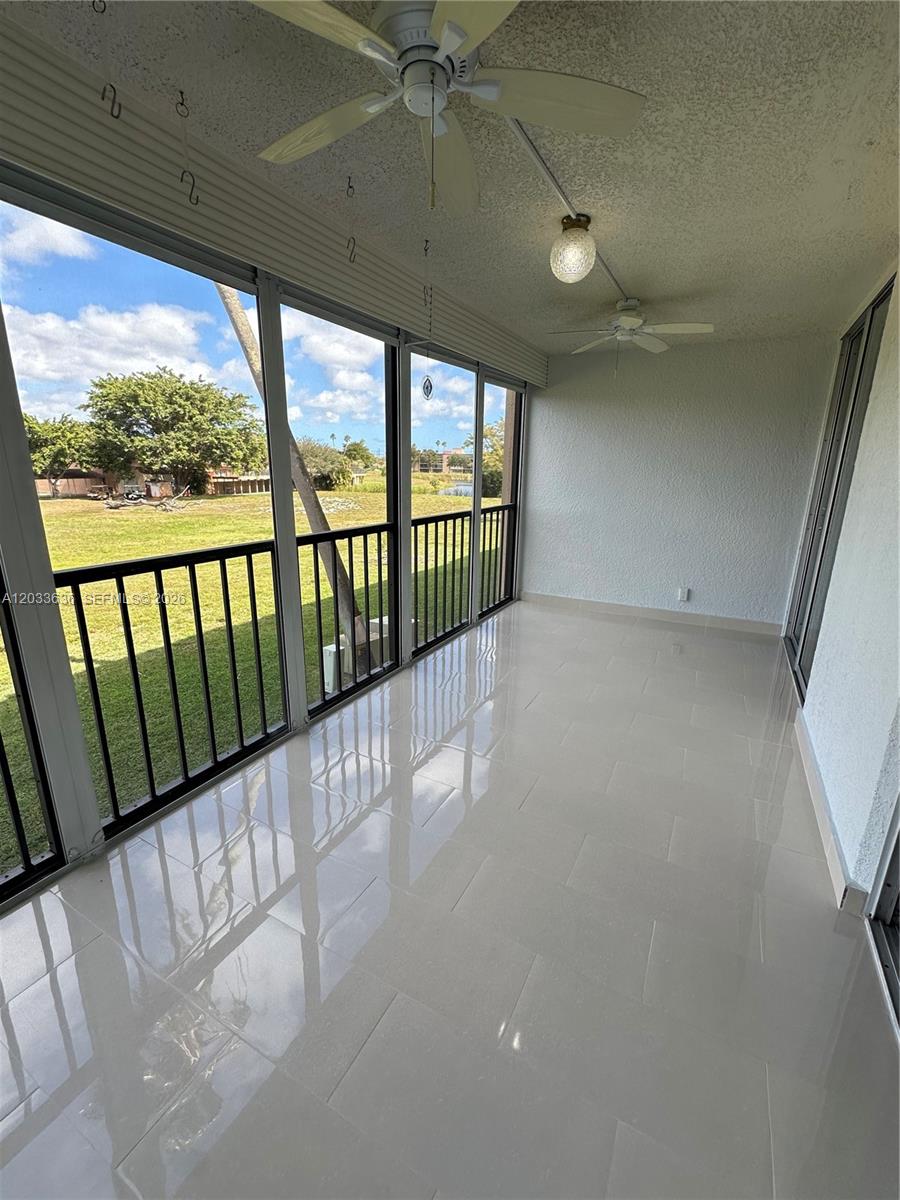 A screened-in balcony features light-colored tile flooring, two ceiling fans, and views of a grassy yard — 7561 NW 1st St # 204, Margate FL 33063, MARGATE, FL