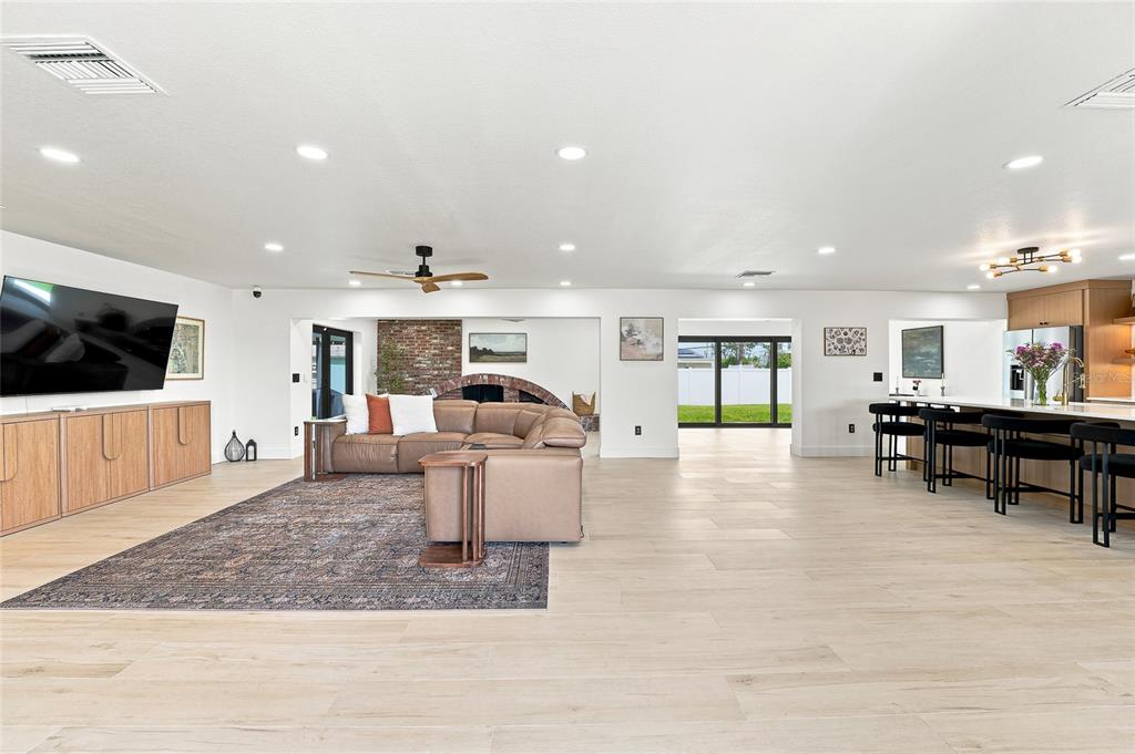 An open-concept living room and kitchen featuring a brown sectional, brick wall, and island — 6241 TANGLEWOOD DRIVE NE, ST PETERSBURG, FL