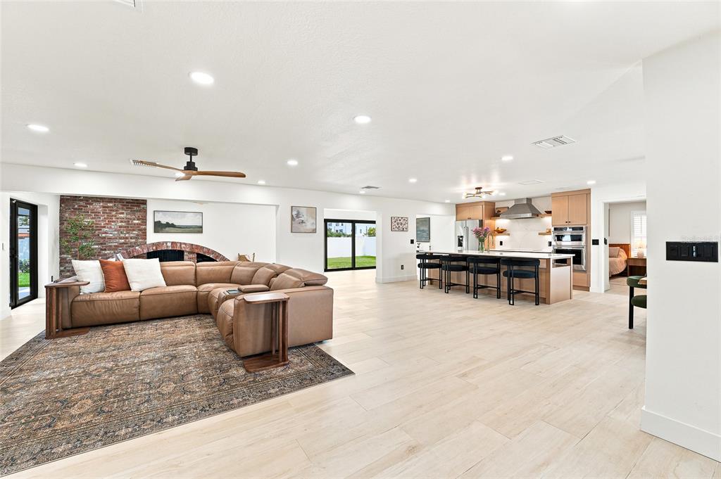 An open-concept living room and kitchen featuring a large sectional sofa and wood-look flooring — 6241 TANGLEWOOD DRIVE NE, ST PETERSBURG, FL