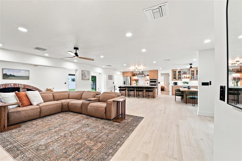 An open-concept living room features light wood floors, a brick fireplace, and a kitchen island — 6241 TANGLEWOOD DRIVE NE, ST PETERSBURG, FL