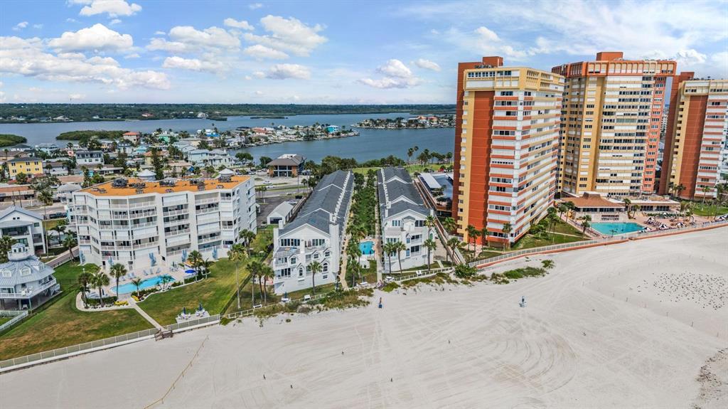 An aerial view shows beachfront high-rise and low-rise condominiums with pools near the ocean — 17960 GULF BOULEVARD UNIT 121, REDINGTON SHORES, FL