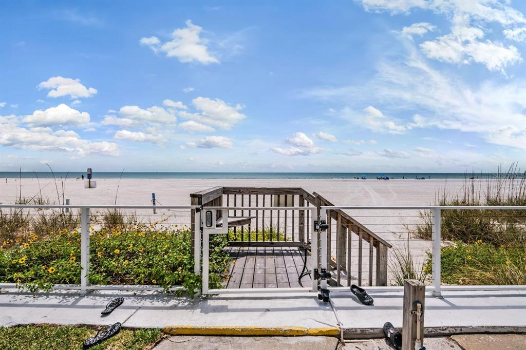 A wooden gate and staircase lead from a patio directly onto a sandy beach — 17960 GULF BOULEVARD UNIT 121, REDINGTON SHORES, FL