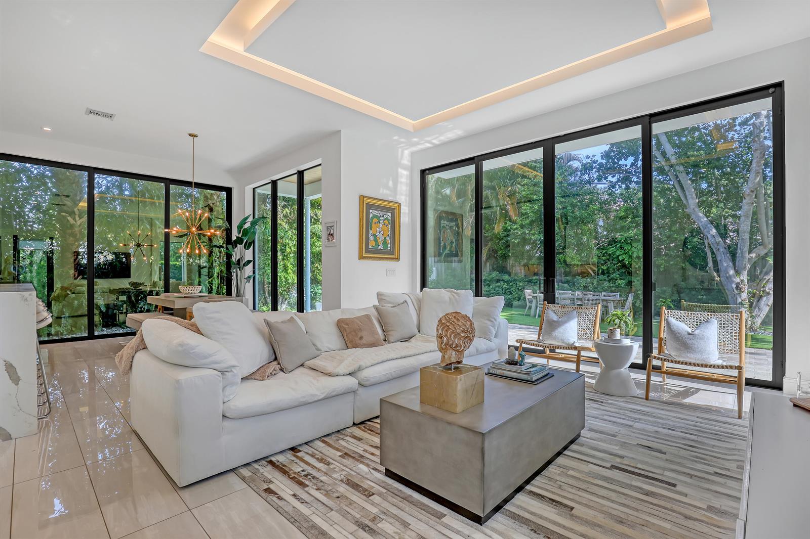 A modern living room features a white sectional sofa, concrete coffee table, and floor-to-ceiling windows — 703 NE 5th Street, Delray Beach FL 33483, DELRAY BEACH, FL