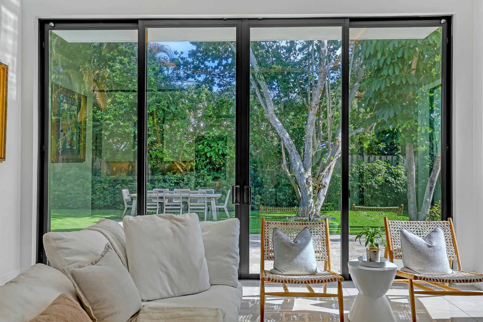 A living room with a white sofa and two chairs faces large glass sliding doors — 703 NE 5th Street, Delray Beach FL 33483, DELRAY BEACH, FL