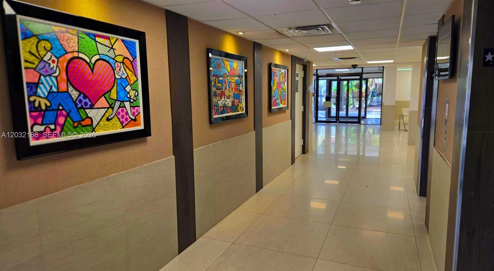 A hallway features tiled floors, recessed lighting, and three colorful paintings on the wall — 4164 Inverrary Dr # 204, Lauderhill FL 33319, LAUDERHILL, FL