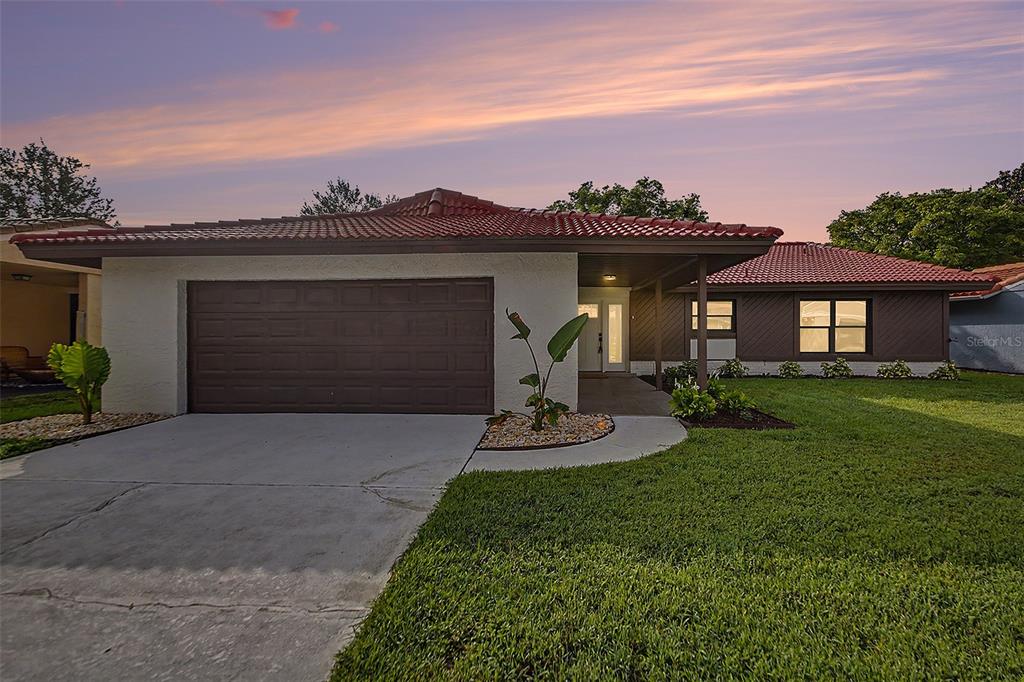 A single-story house with a brown tile roof, a two-car garage, and a front lawn — 10604 WHITMAN CIRCLE, ORLANDO, FL