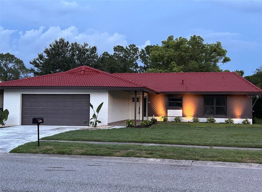 A single-story house with a red tile roof, white stucco, and brown wood siding — 10604 WHITMAN CIRCLE, ORLANDO, FL