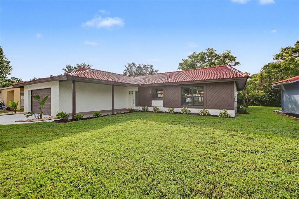 A single-story house with a red tile roof, brown siding, and a covered front porch — 10604 WHITMAN CIRCLE, ORLANDO, FL