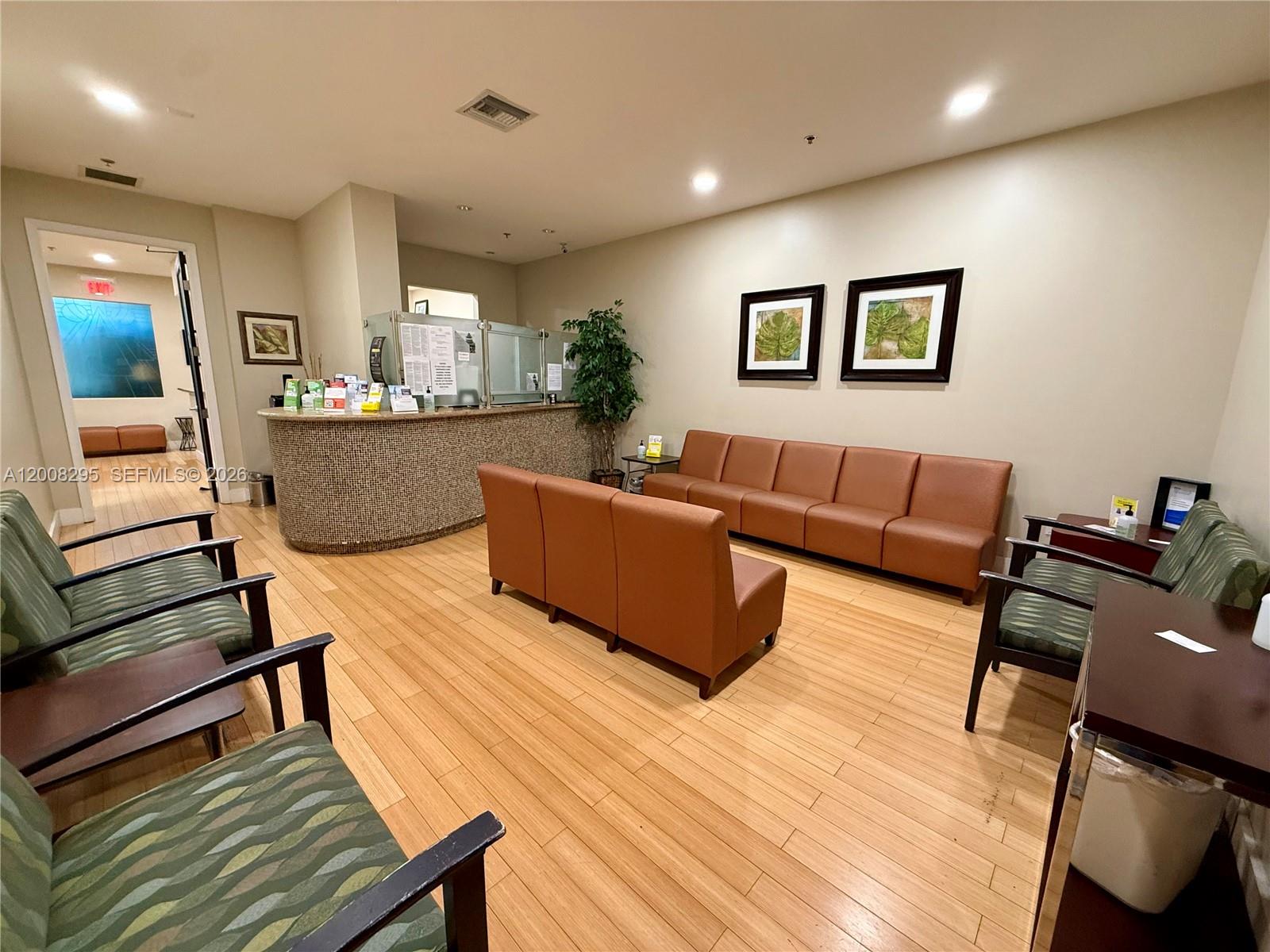 A waiting room features a curved reception desk, brown modular seating, and light wood flooring — 8501 SW 124th Ave # 112A, Miami FL 33183, MIAMI, FL