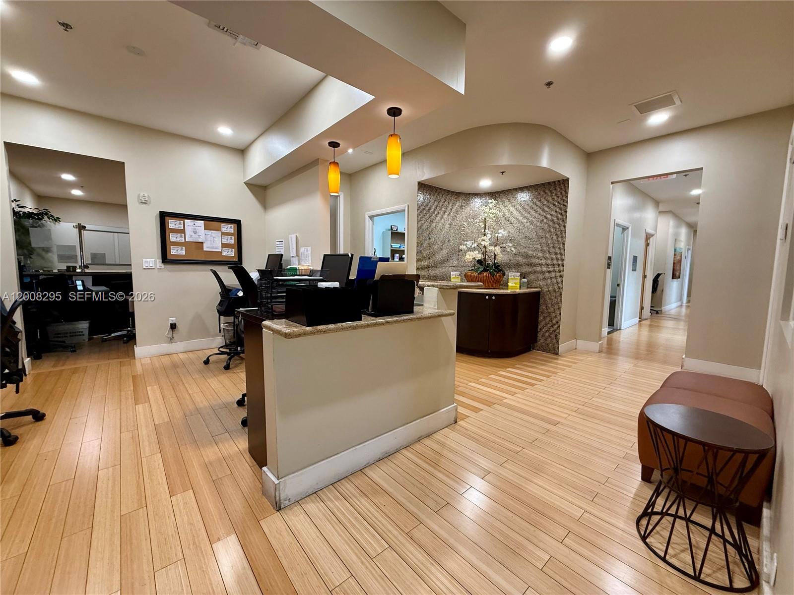A reception area features a desk, wood flooring, and a decorative tiled alcove with flowers — 8501 SW 124th Ave # 112A, Miami FL 33183, MIAMI, FL