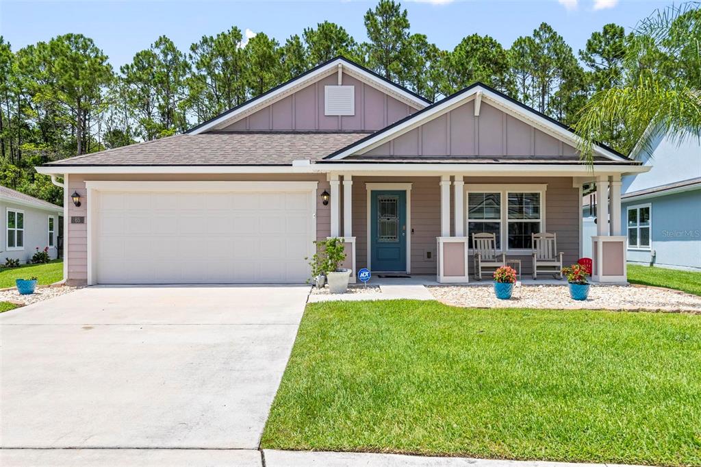 A single-story house with a two-car garage, light brown siding, and a covered front porch — 65 LOB WEDGE LANE, BUNNELL, FL