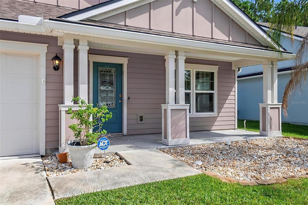 A front porch with a teal door, white columns, and a potted plant — 65 LOB WEDGE LANE, BUNNELL, FL