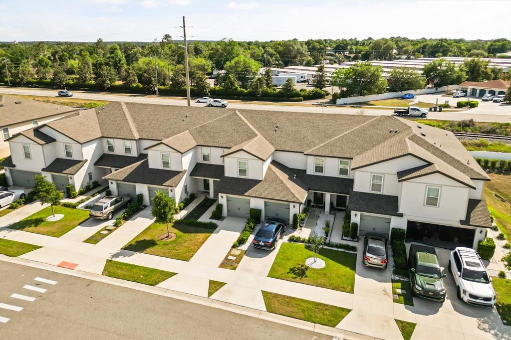 An aerial view of a multi-unit townhouse complex with attached garages and paved driveways — 1758 WITHERNSEA COURT, TAVARES, FL