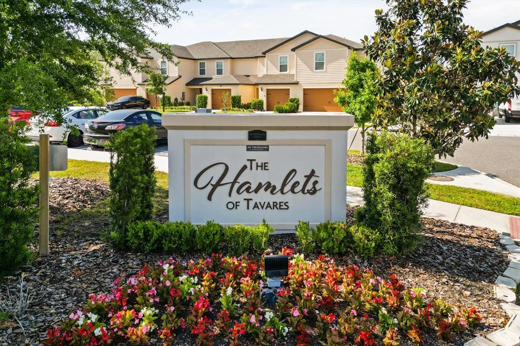 A sign for The Hamlets of Tavares stands in front of townhomes and parked cars — 1758 WITHERNSEA COURT, TAVARES, FL