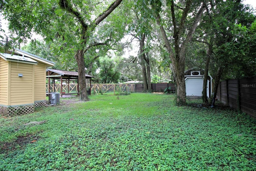 A backyard features a yellow house, a wooden gazebo, a shed, and mature trees — 17091 SW 138TH LANE, ARCHER, FL