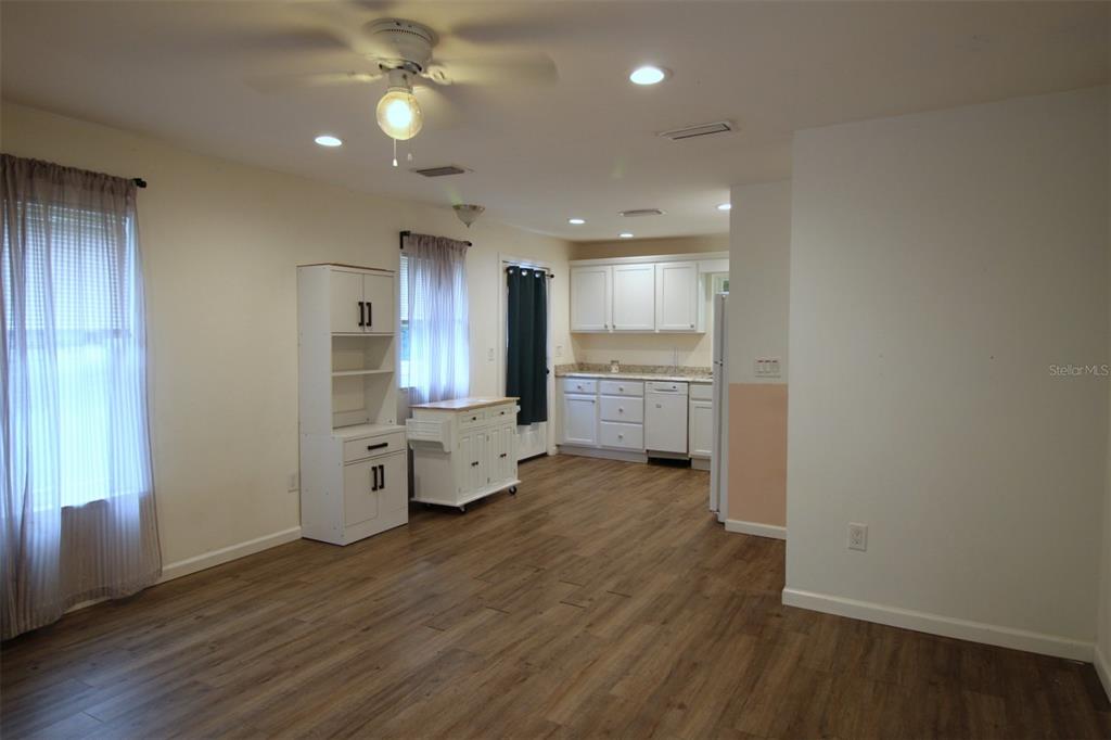 An open-concept kitchen and dining area features white cabinetry, wood-look flooring, and a ceiling fan — 17091 SW 138TH LANE, ARCHER, FL