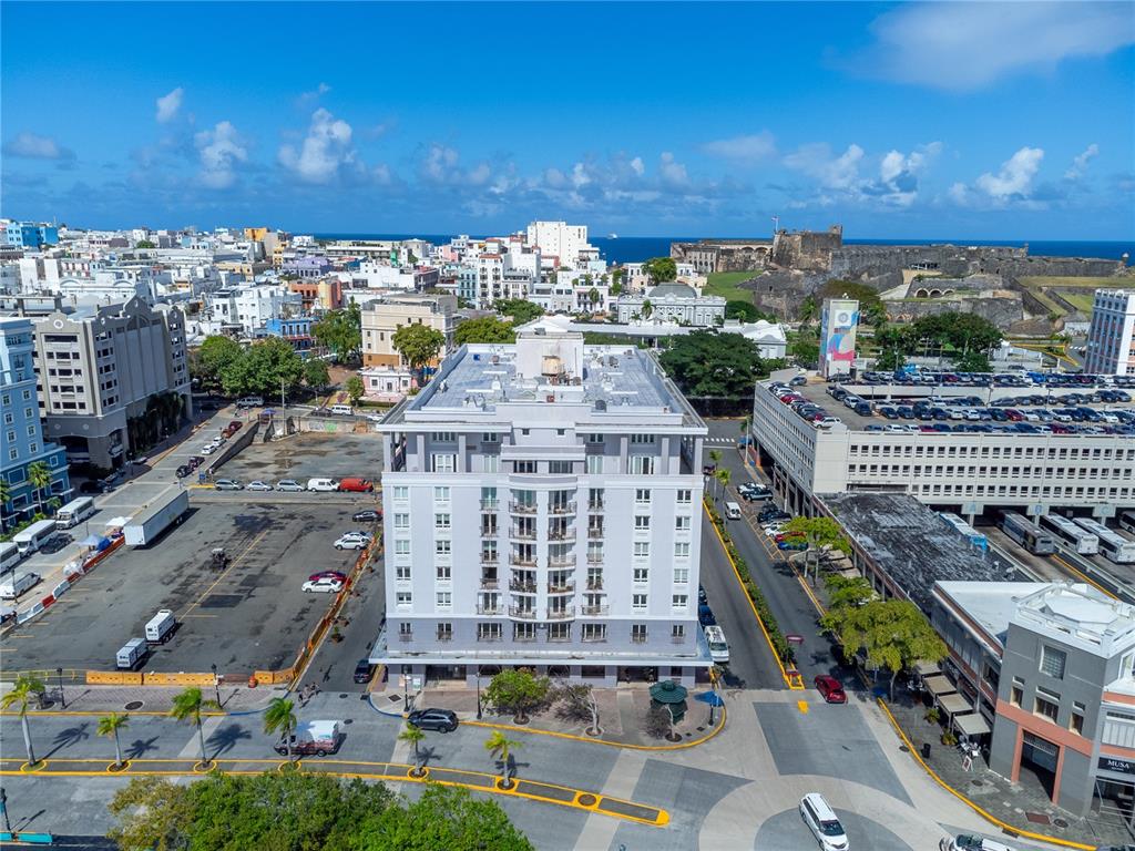 An aerial view shows a multi-story gray apartment building surrounded by city streets and parking — 100 REINA DE CASTILLA UNIT 308, SAN JUAN, PR