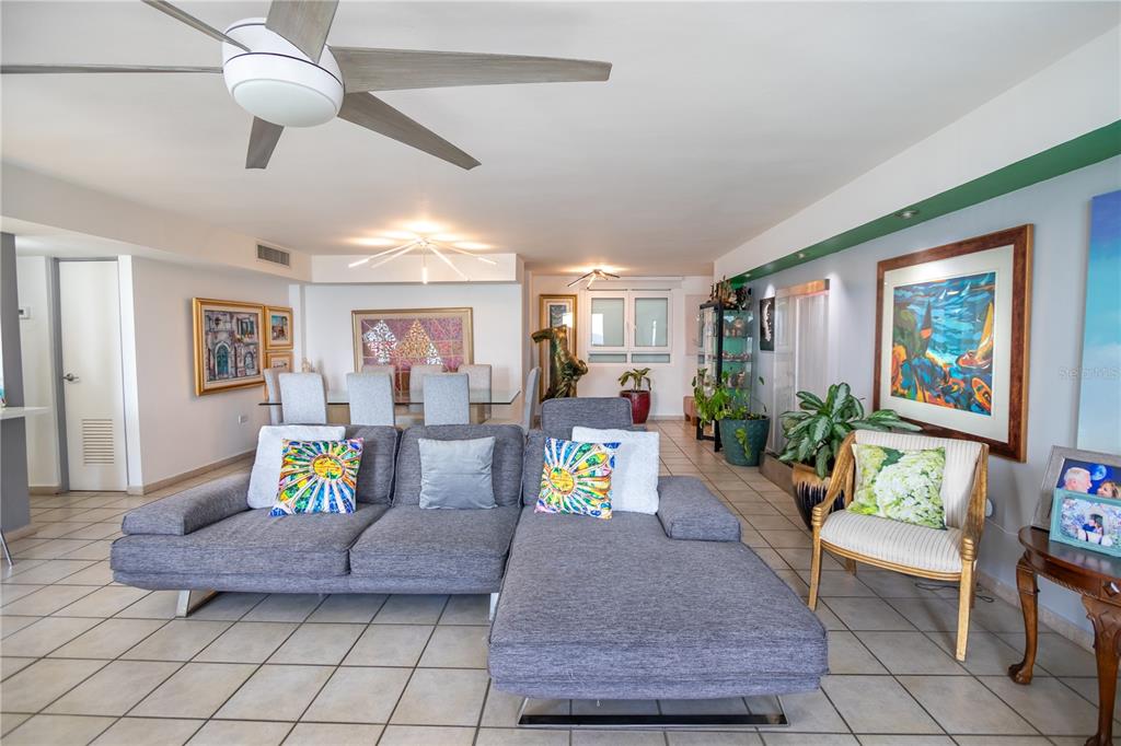 A living room features a grey sectional sofa, tile flooring, and a dining area beyond — 100 REINA DE CASTILLA UNIT 308, SAN JUAN, PR