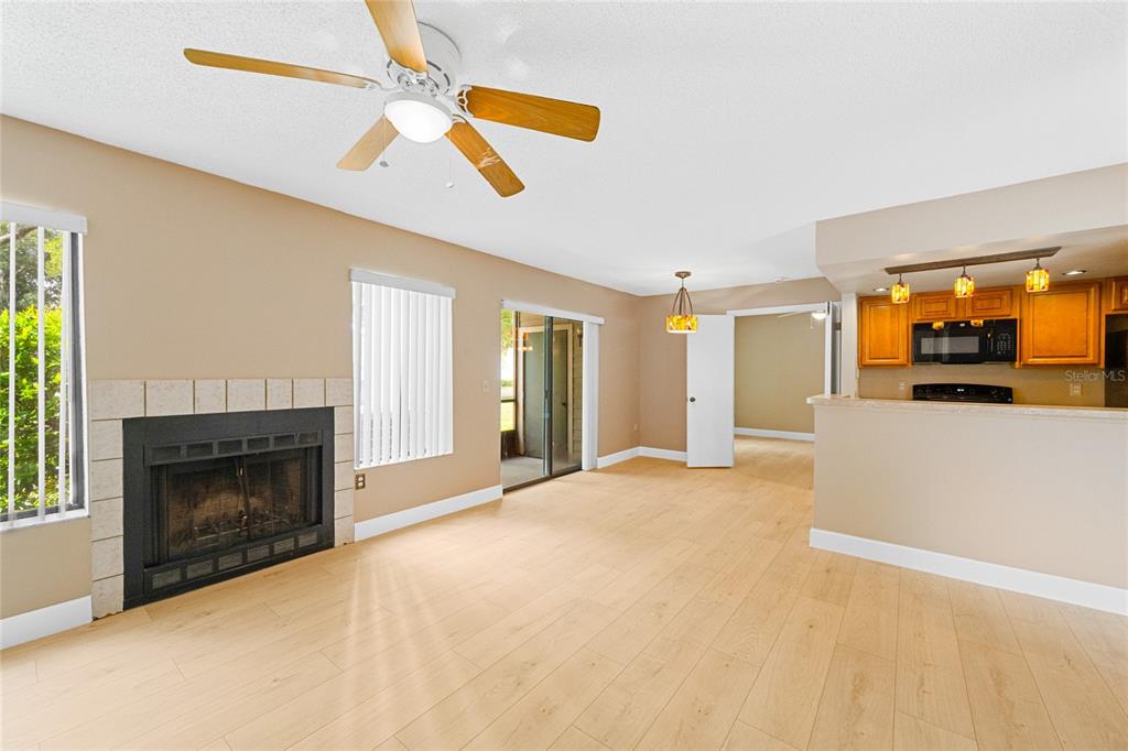 A living room with light wood flooring, a fireplace, and an open kitchen area — 543 SUN RIDGE PLACE UNIT 102, ALTAMONTE SPRINGS, FL