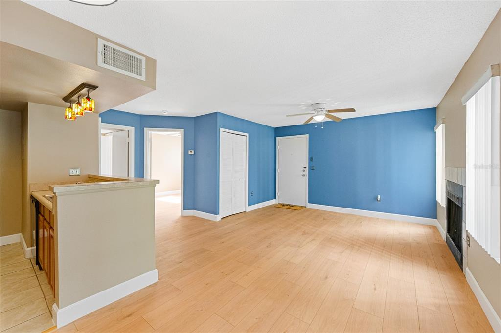 An open-concept living room features blue walls, light wood flooring, and a kitchen breakfast bar — 543 SUN RIDGE PLACE UNIT 102, ALTAMONTE SPRINGS, FL
