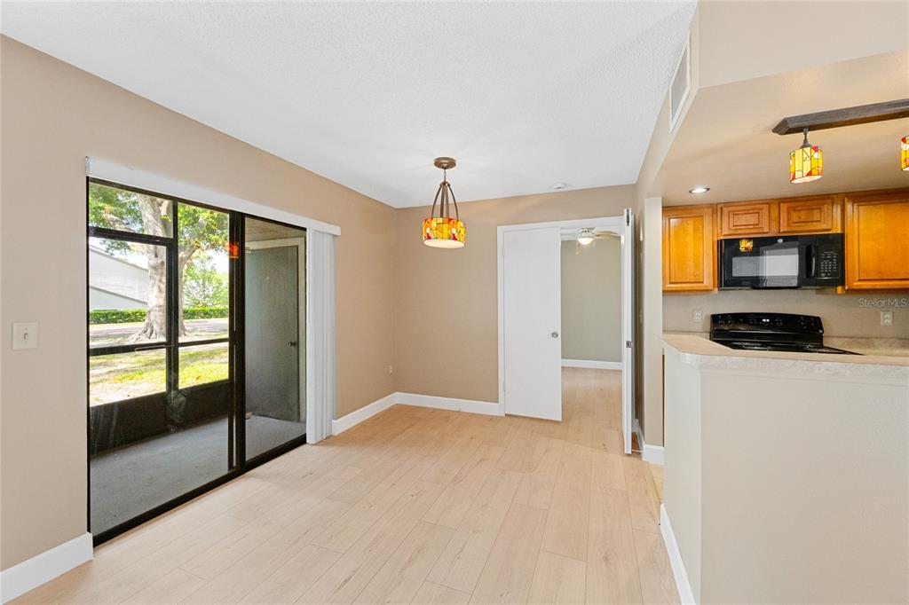A dining area with light wood flooring, a sliding glass door, and an adjacent kitchen — 543 SUN RIDGE PLACE UNIT 102, ALTAMONTE SPRINGS, FL