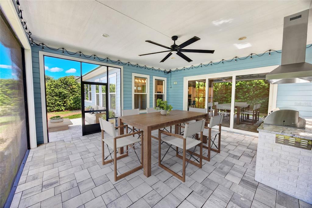 A covered outdoor patio features a dining set, a grill, and blue siding — 11872 SW 33RD LANE, GAINESVILLE, FL