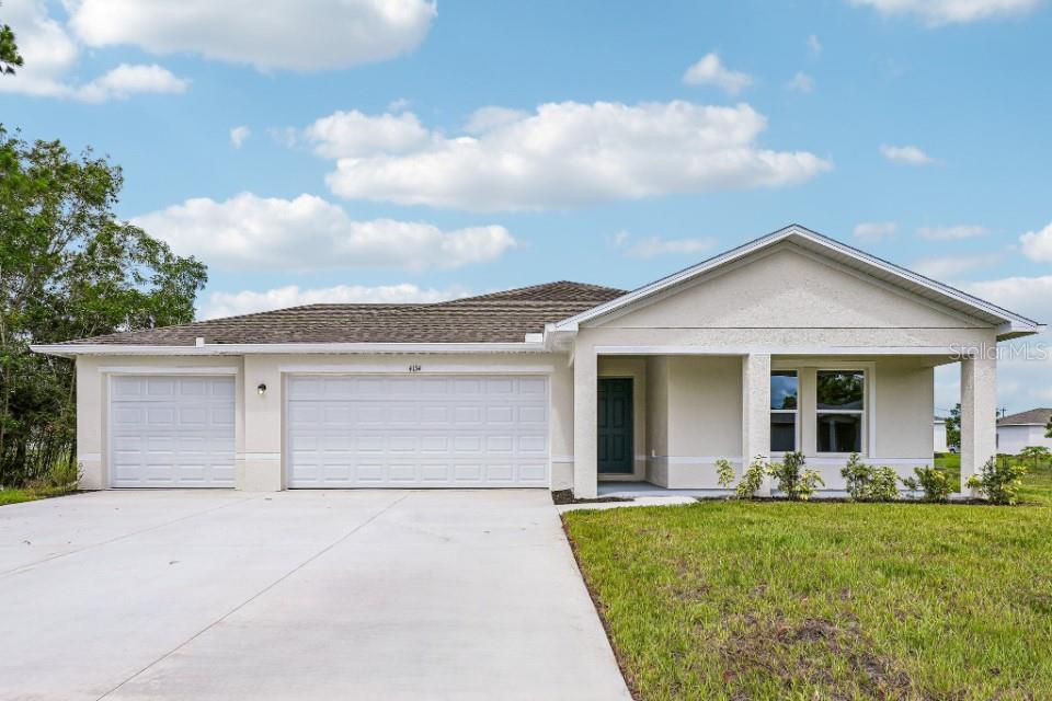 A single-story house with a three-car garage, light stucco exterior, and a covered front porch — 25346 CADIZ DRIVE, PUNTA GORDA, FL