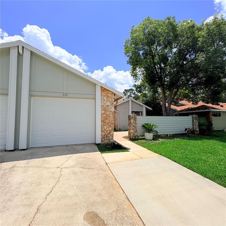 A light-colored house exterior features a garage, stone accents, and a concrete driveway — 229 SURF SCOOTER DRIVE, DAYTONA BEACH, FL