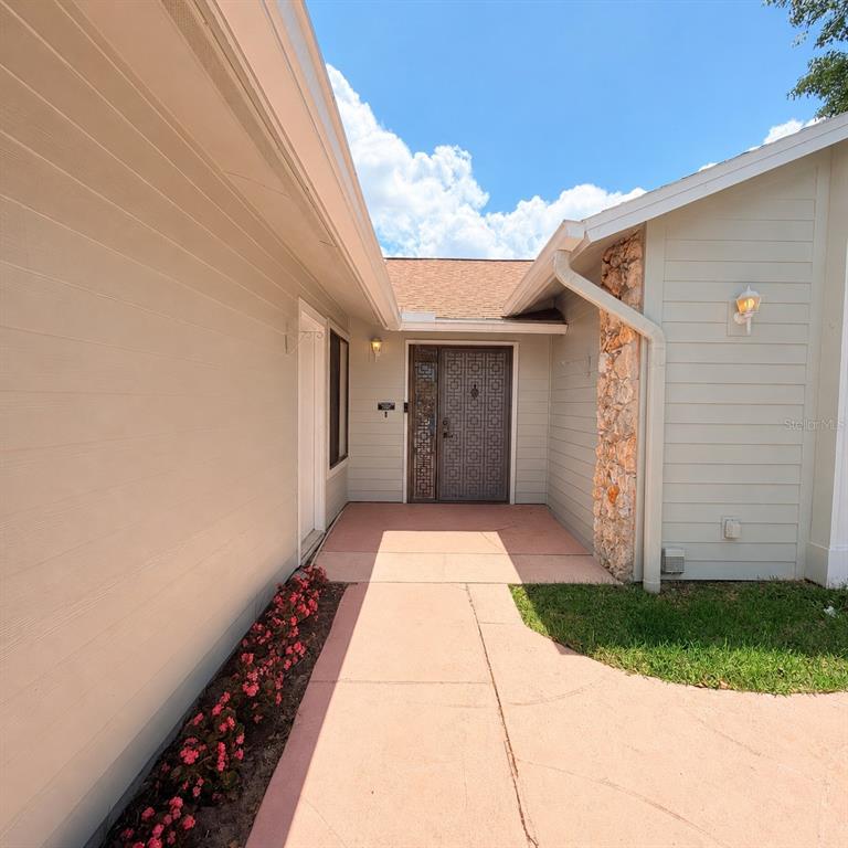 A walkway leads to the front entrance of a house with light-colored siding and stone — 229 SURF SCOOTER DRIVE, DAYTONA BEACH, FL