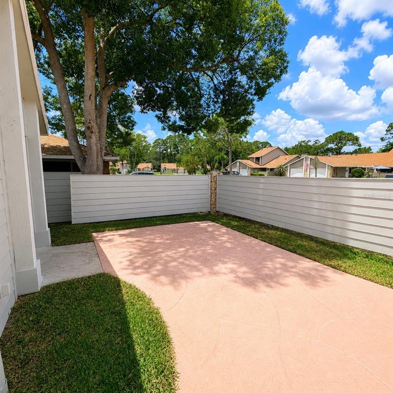 A backyard patio with a pink concrete surface enclosed by a white horizontal fence — 229 SURF SCOOTER DRIVE, DAYTONA BEACH, FL