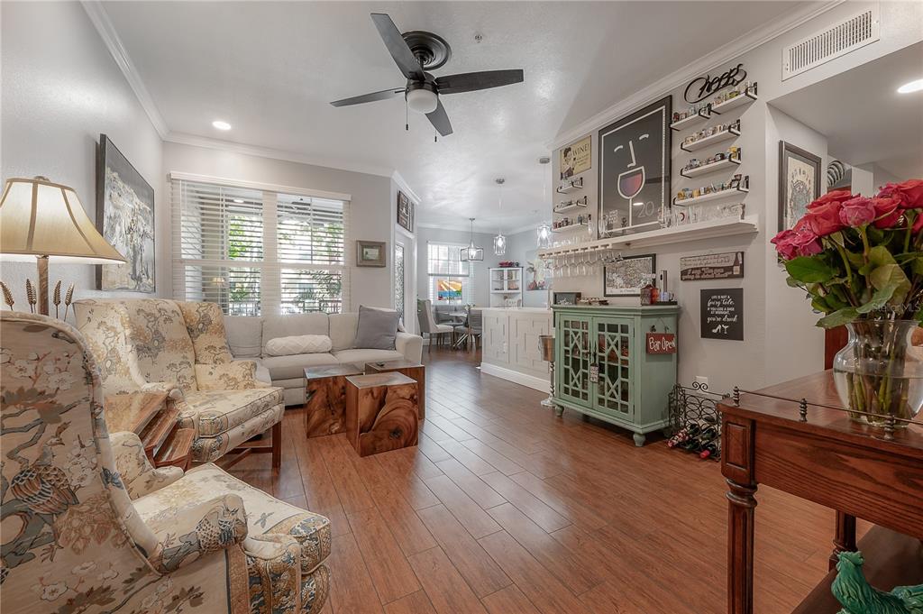 A living room features wood-look tile flooring, a ceiling fan, and a built-in bar area — 1810 E PALM AVENUE UNIT 4103, TAMPA, FL
