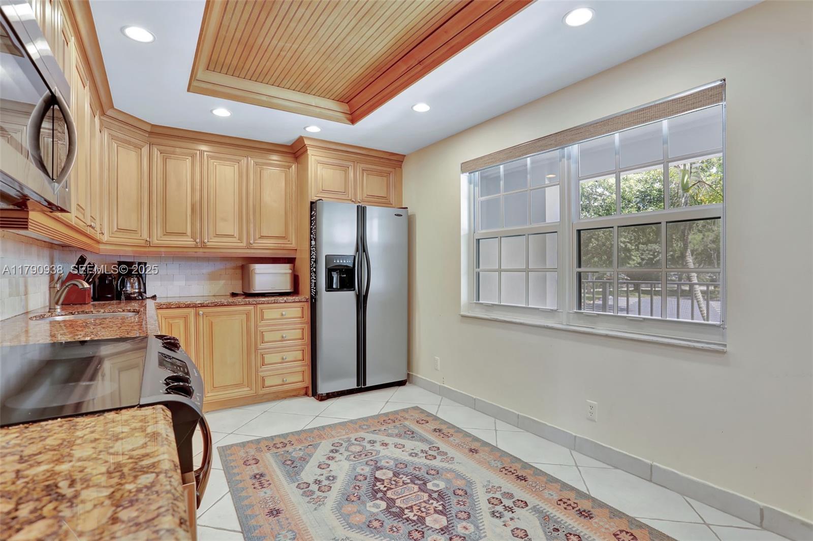 A kitchen features light wood cabinets, granite countertops, stainless steel appliances, and a patterned rug — 4020 W Palm Aire Dr # 204, Pompano Beach FL 33069, POMPANO BEACH, FL