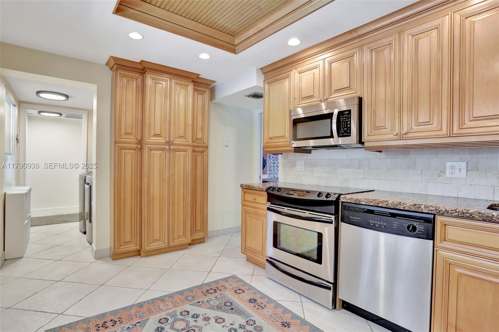 A kitchen features light wood cabinets, stainless steel appliances, granite countertops, and a tile floor — 4020 W Palm Aire Dr # 204, Pompano Beach FL 33069, POMPANO BEACH, FL