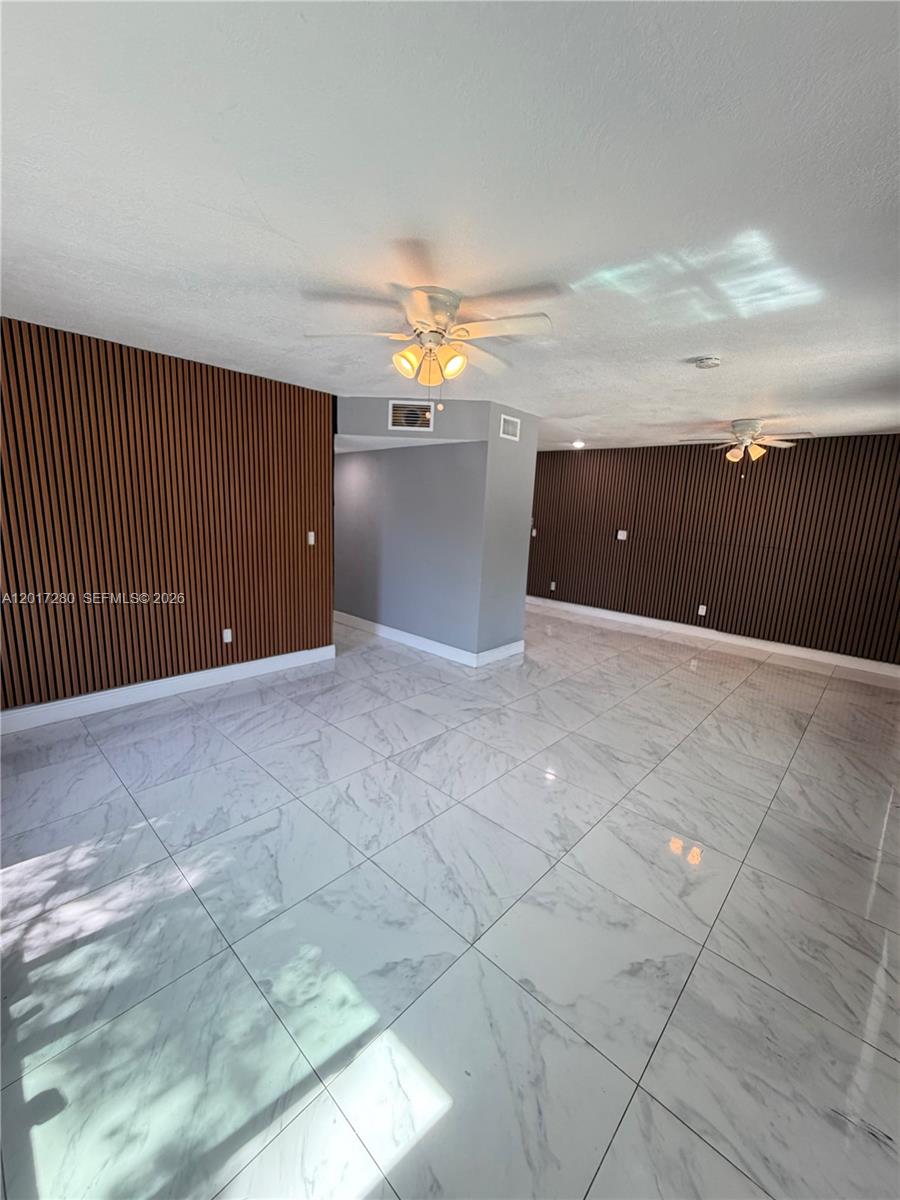 A room with white marble-style tile flooring and walls accented with vertical wood slats — 850 NW 113th St, Miami FL 33168, MIAMI, FL