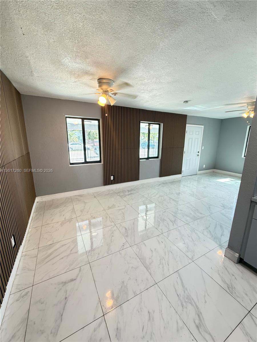 A room with white marble-style tile floors and wood slat accent walls — 850 NW 113th St, Miami FL 33168, MIAMI, FL