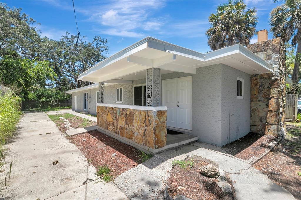 A single-story house with a stone-accented porch, white double doors, and a stone chimney — 7541 PIER ROAD, PORT RICHEY, FL