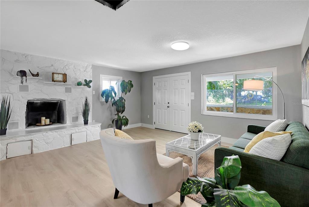 A living room features a white stone fireplace, light wood flooring, and a green sofa — 7541 PIER ROAD, PORT RICHEY, FL