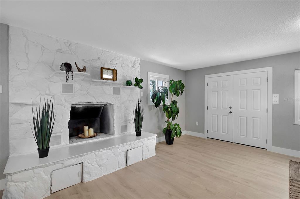A living room features a white stone fireplace, light wood flooring, and double entry doors — 7541 PIER ROAD, PORT RICHEY, FL