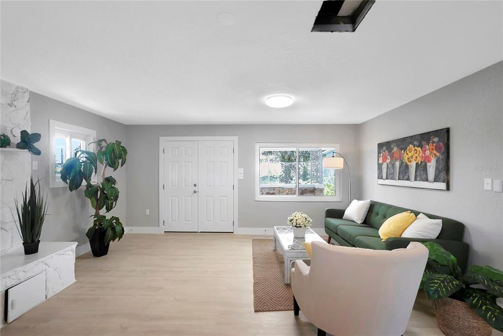 A living room features light wood flooring, gray walls, a green sofa, and double entry doors — 7541 PIER ROAD, PORT RICHEY, FL