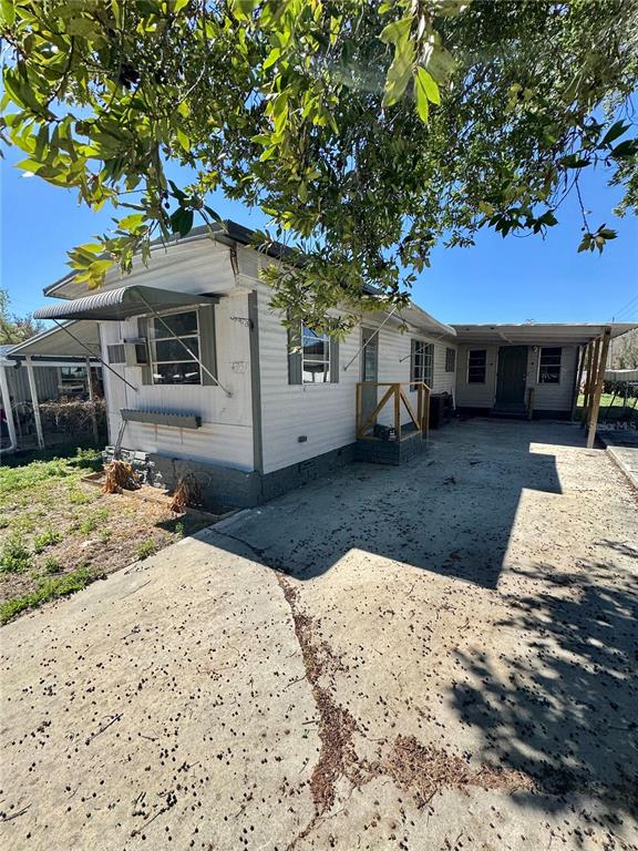 A single-story mobile home with a concrete driveway, metal awning, and a wooden porch railing — 4951 PATIO DRIVE, ZEPHYRHILLS, FL