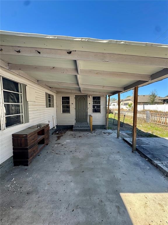 A covered concrete patio area sits in front of a house with light-colored siding — 4951 PATIO DRIVE, ZEPHYRHILLS, FL