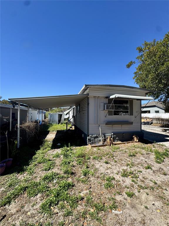 A mobile home with a metal carport and a window air conditioning unit — 4951 PATIO DRIVE, ZEPHYRHILLS, FL