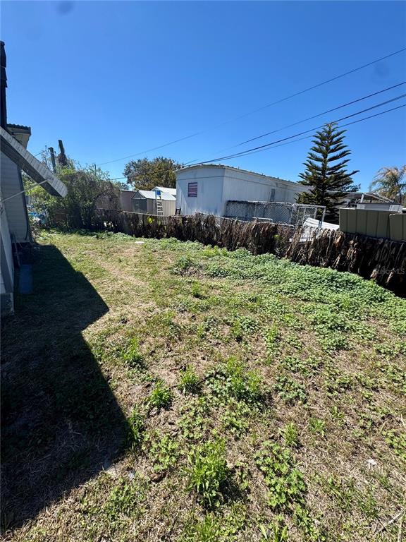 An outdoor view shows a grassy backyard with a chain-link fence and a mobile home — 4951 PATIO DRIVE, ZEPHYRHILLS, FL