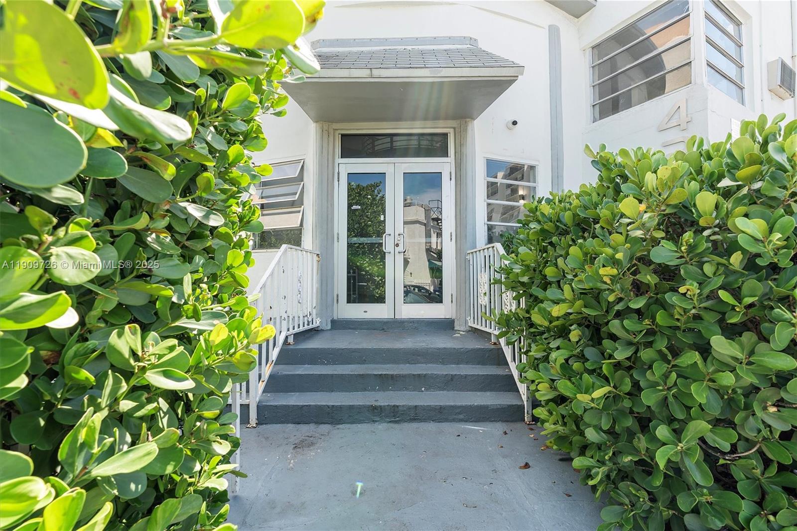 A set of concrete stairs leads to a glass double door entrance with a canopy — 420 78th St, Miami Beach FL 33141, MIAMI BEACH, FL