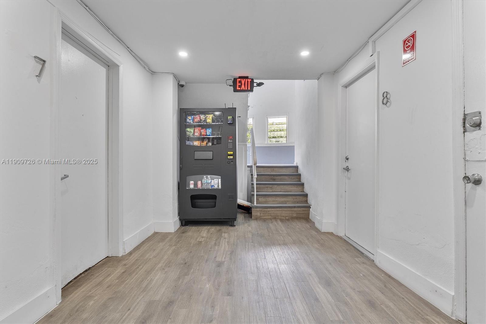 A hallway features wood-look flooring, two white doors, a vending machine, and a staircase — 420 78th St, Miami Beach FL 33141, MIAMI BEACH, FL