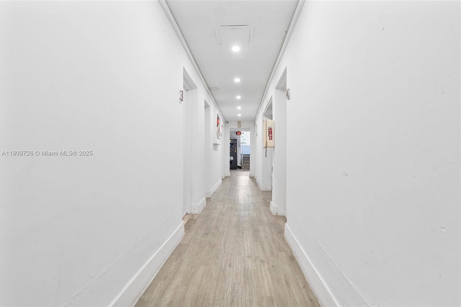 A long, narrow hallway features white walls, light wood-look flooring, and recessed ceiling lighting — 420 78th St, Miami Beach FL 33141, MIAMI BEACH, FL
