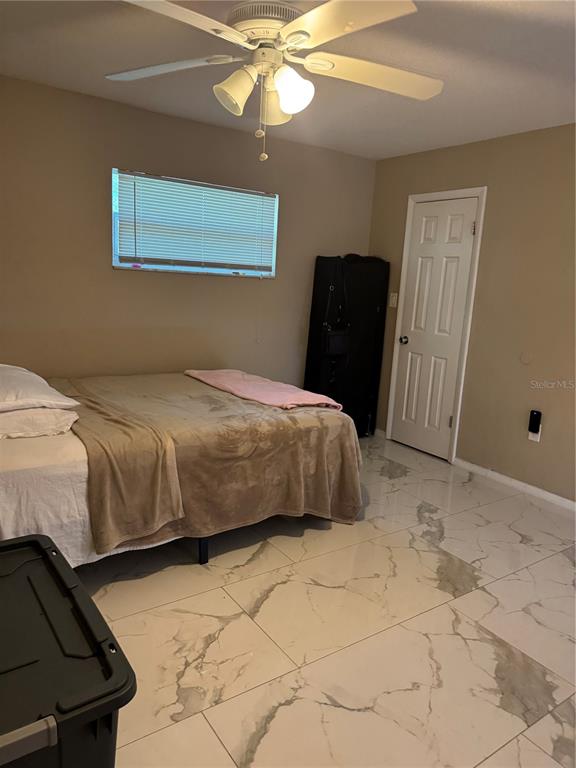 A bedroom features a bed, a ceiling fan, and white marble-patterned tile flooring — 1016 KIRK STREET, ORLANDO, FL