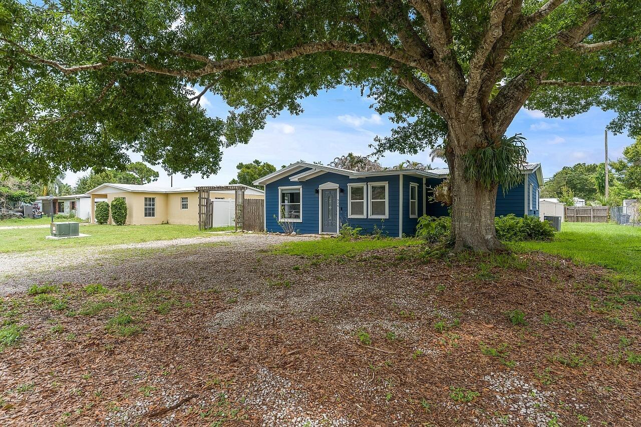 A blue house with a gravel driveway sits under a large tree — 926 37th Avenue, Vero Beach FL 32960, VERO BEACH, FL