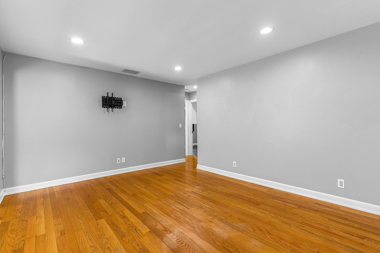 An empty room features gray walls, hardwood floors, recessed lighting, and a wall-mounted television bracket — 926 37th Avenue, Vero Beach FL 32960, VERO BEACH, FL