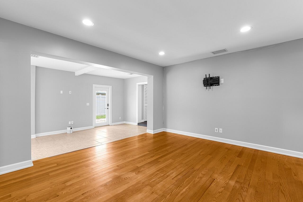 An empty living room with hardwood floors, gray walls, recessed lighting, and a wall-mounted television bracket — 926 37th Avenue, Vero Beach FL 32960, VERO BEACH, FL